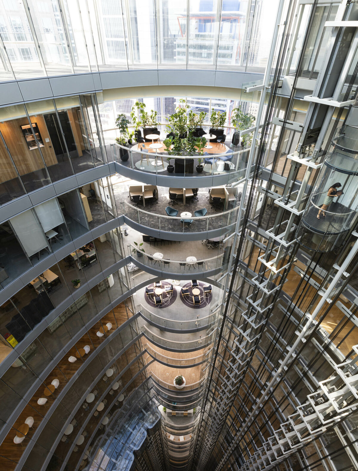 A cascading atrium of collaborative terraces, soft lounge areas, and planting, forming a transparent living spine that connects multiple levels and supports focused work, casual meetings and moments of rest.