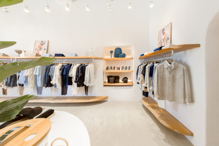 A refined retail display featuring natural wood shelving, soft-toned apparel, and thoughtfully placed accessories. The minimalist design highlights the quality of each piece, while warm lighting enhances the inviting ambience of the space.