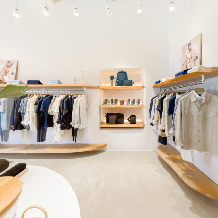 A refined retail display featuring natural wood shelving, soft-toned apparel, and thoughtfully placed accessories. The minimalist design highlights the quality of each piece, while warm lighting enhances the inviting ambience of the space.