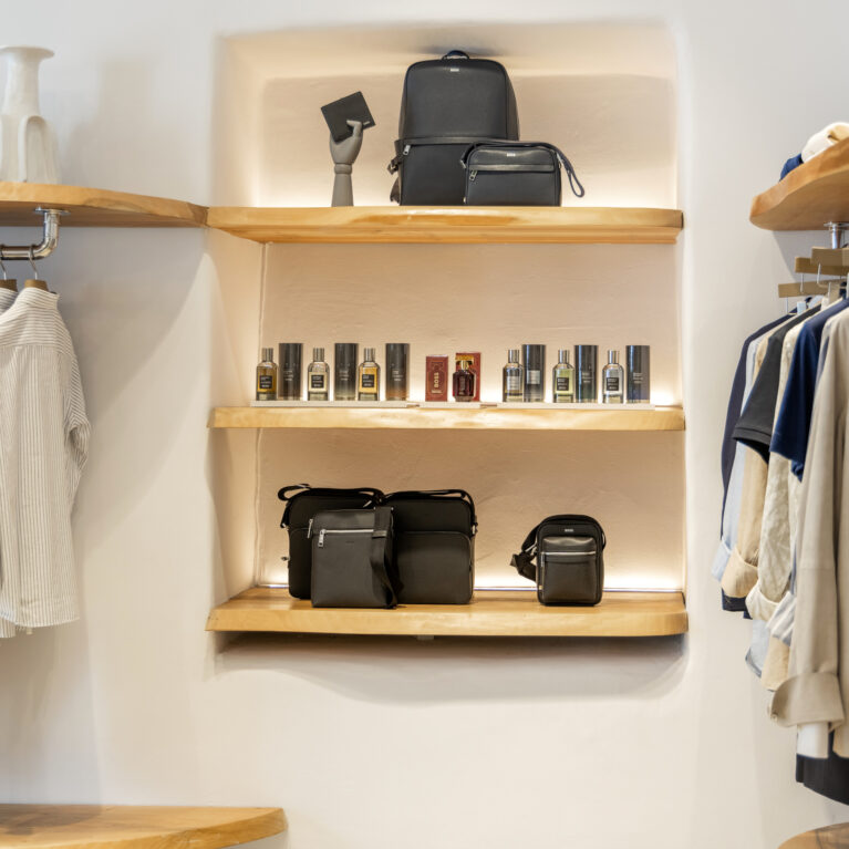 A refined product display featuring raw-edged wooden shelving, soft recessed lighting, and a neutral backdrop, elevating luxury accessories and fragrances with an organic touch.