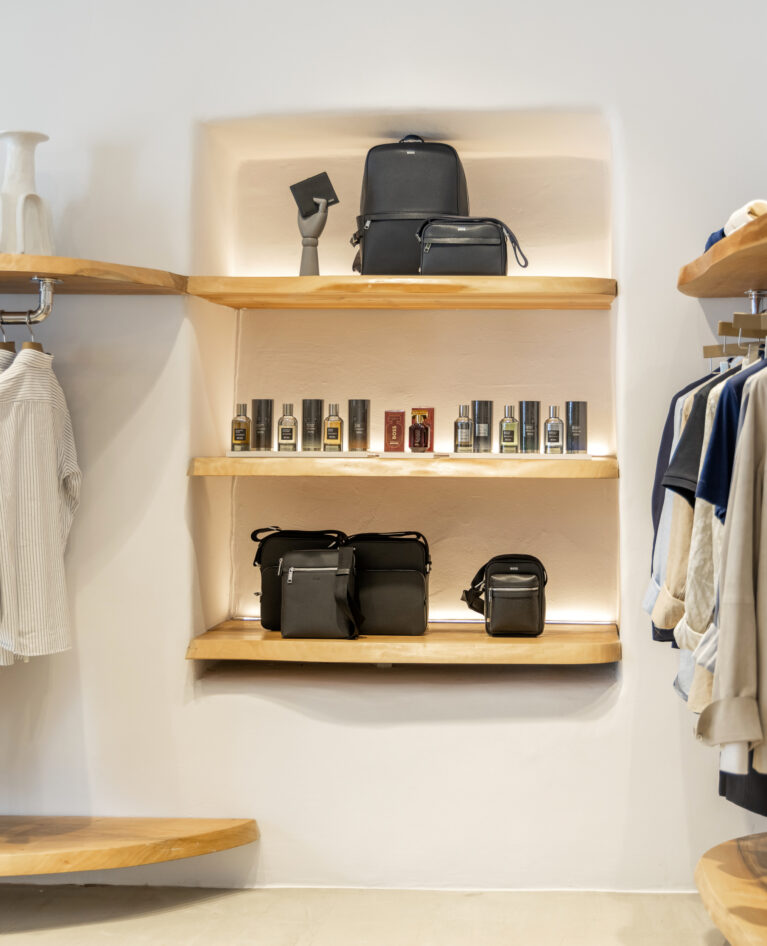 A refined product display featuring raw-edged wooden shelving, soft recessed lighting, and a neutral backdrop, elevating luxury accessories and fragrances with an organic touch.