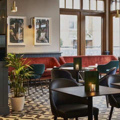 A low-level lounge layout showcasing patterned tiling and rich velvet banquettes.
