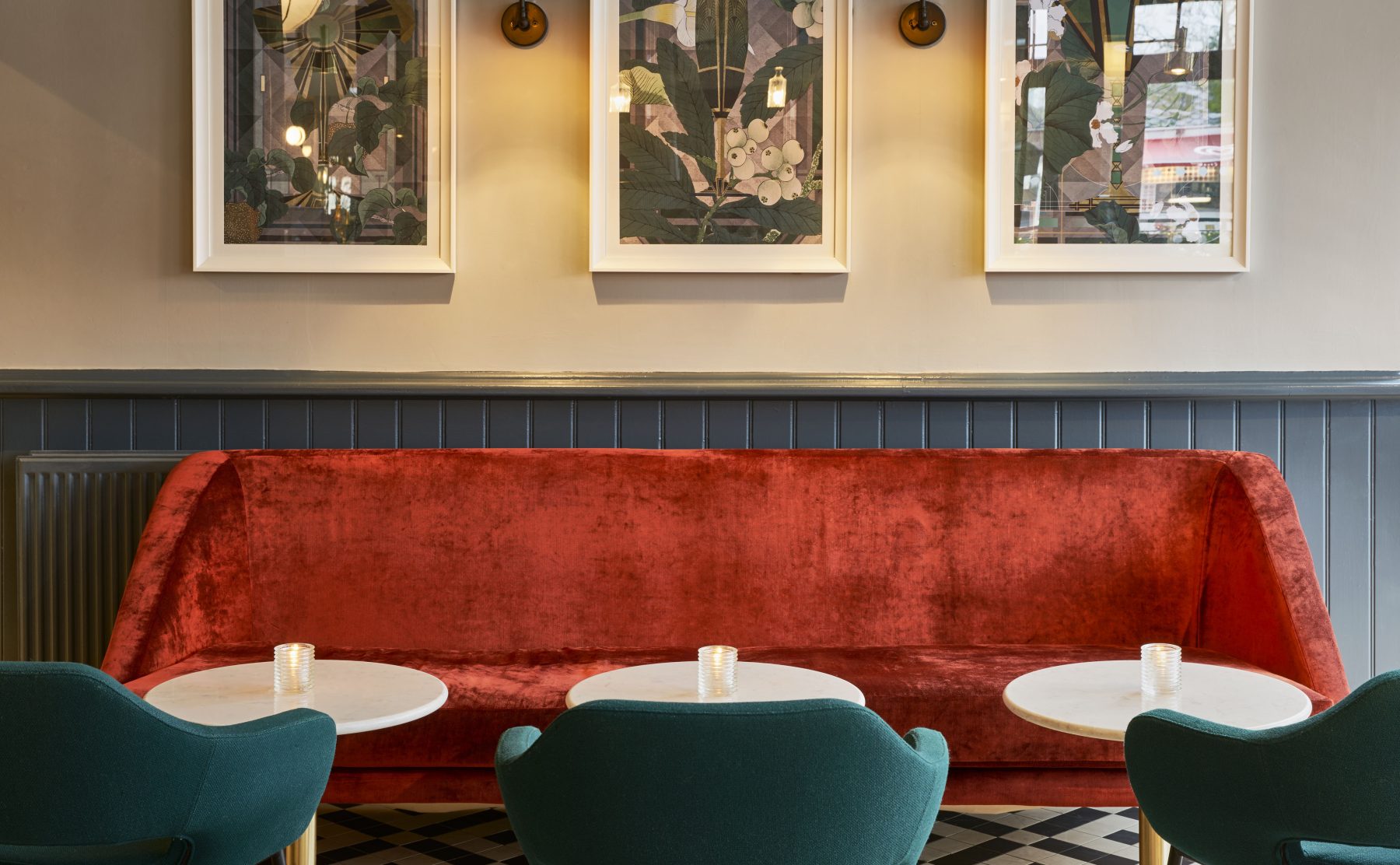 Velvet lounge sofa, Banquette seating, Checkered tile floor, Brass wall sconces, Marble bistro tables, Dark wainscoting paneling, Teal armchairs, Hospitality interior design, Windsor brasserie bar, Botanical wall art