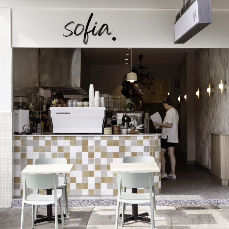 Sofia’s open façade features soft earthy tones and textured tiles, creating a warm and inviting first impression. The minimal “Sophia” logo complements the modern design, while fresh flowers and pastel seating add a welcoming touch.