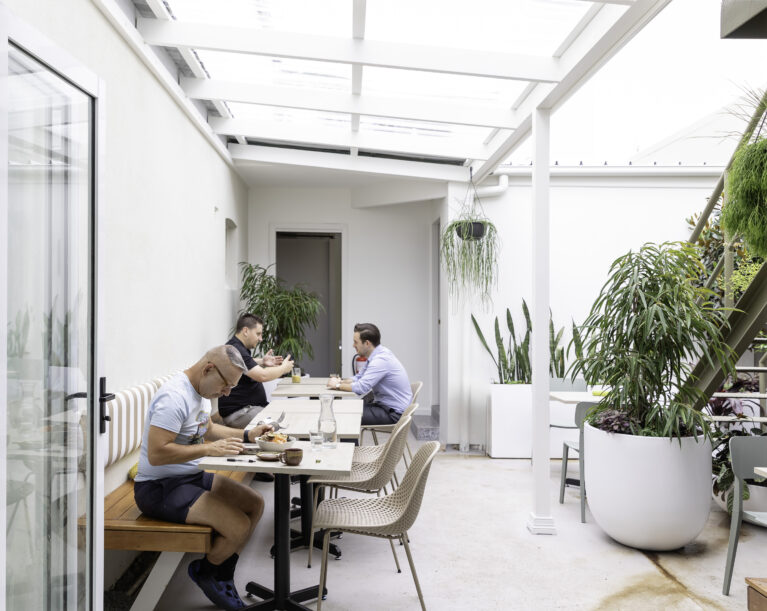 Sofia’s courtyard features light-filled seating with natural greenery and clean design. Striped benches, neutral tones, and modern planters create a welcoming and relaxing outdoor space.