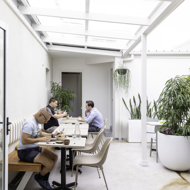 Sofia’s courtyard features light-filled seating with natural greenery and clean design. Striped benches, neutral tones, and modern planters create a welcoming and relaxing outdoor space.