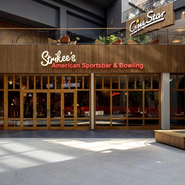Hospitality storefront architecture, timber frame glazing, custom wooden paneling, commercial neon sign, sports bar entrance, mezzanine floor alignment, large format ground tile, integrated venue branding.