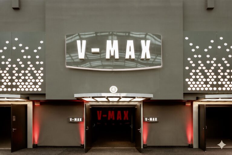 Auditorium entrance portal, backlit cinema marquee, perforated metal cladding, textured charcoal plaster, theatrical light canopy, symmetrical double doors, red ambient wall wash, premium theater branding.