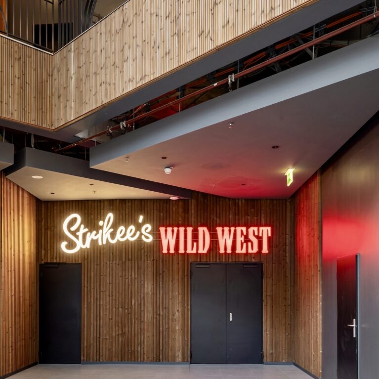 Ground level entertainment concourse, vertical timber paneling, neon signage installation, geometric drop ceiling, commercial restaurant corridor, architectural acoustic cladding, hospitality zoning layout.
