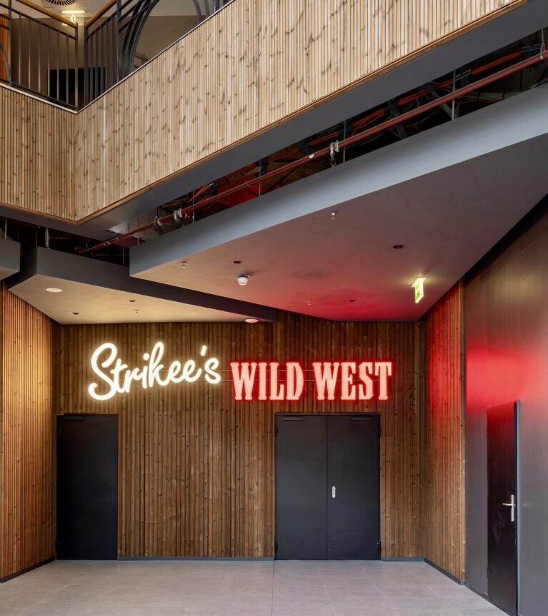 Ground level entertainment concourse, vertical timber paneling, neon signage installation, geometric drop ceiling, commercial restaurant corridor, architectural acoustic cladding, hospitality zoning layout.