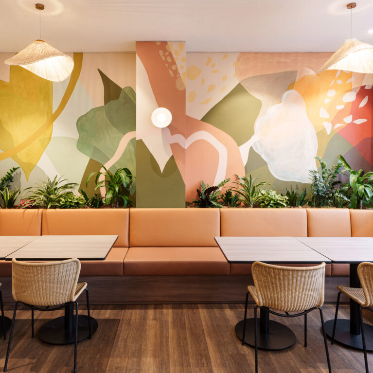 Custom painted mural wall, terracotta leather upholstery, woven rattan dining chairs, integrated planter box, biophilic interior design, woven shade pendant lamps, brass sconce lighting, continuous banquette bench, Sunshine Room fit-out