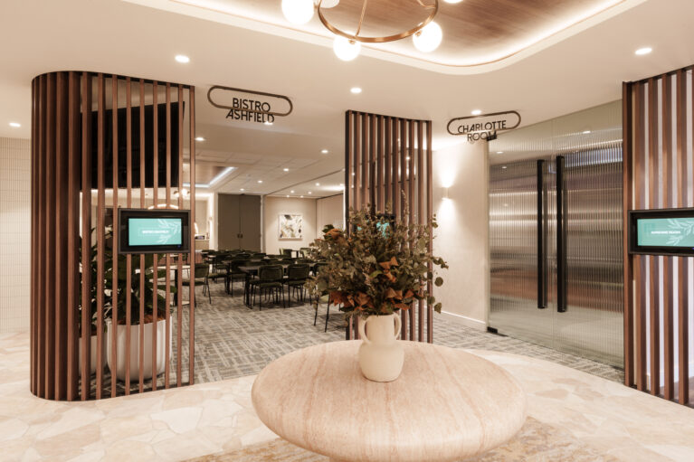 Vertical timber battens, travertine display table, reeded glass doors, crazy paving tile floor, brass ring chandelier, digital wayfinding displays, ceiling cove lighting, venue foyer, function room entry, architectural screen partition