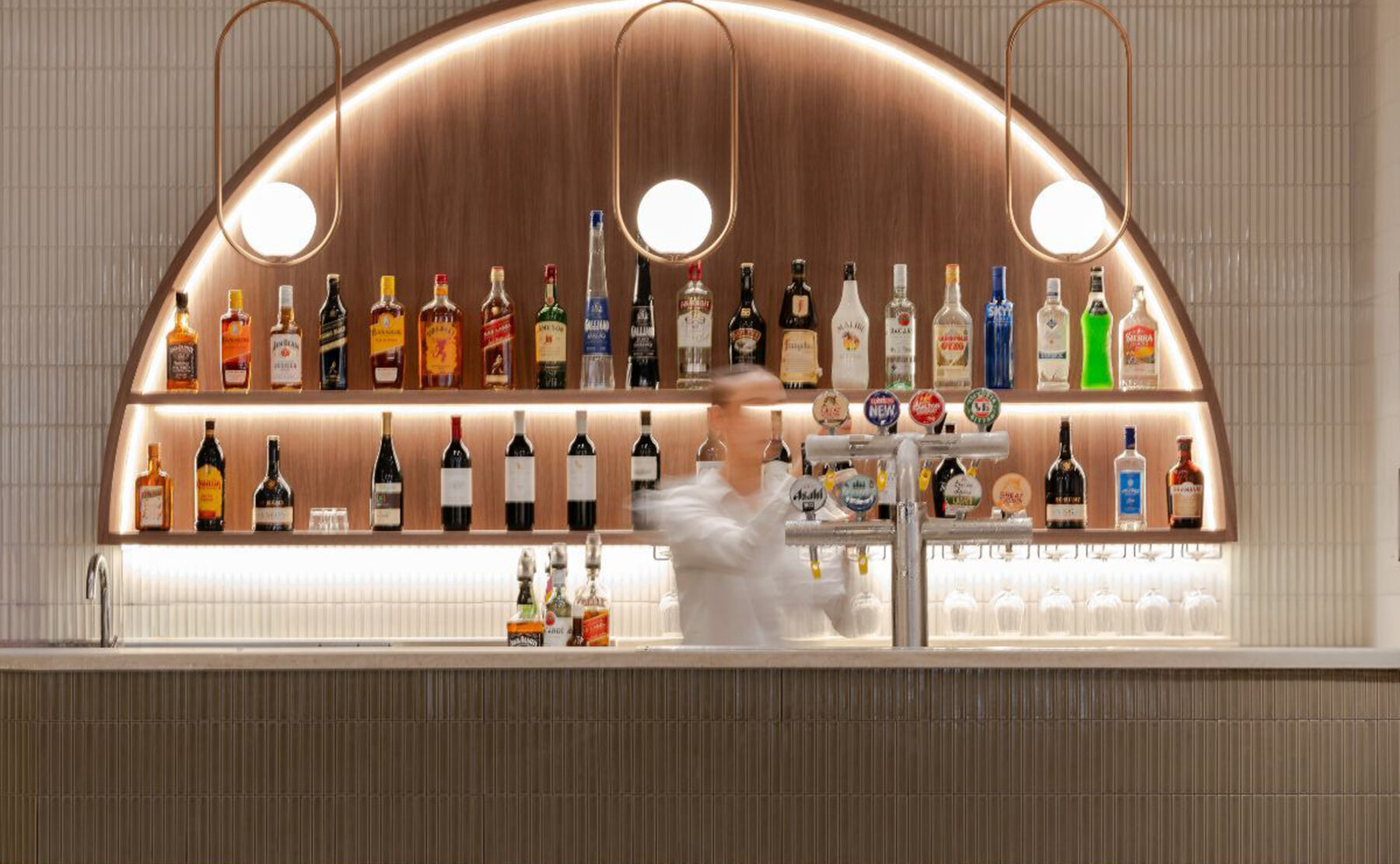 Ribbed cladding, fluted bar front, kit-kat tiles, copper accents, integrated LED lighting, arched display, warm timber veneer, hospitality fit-out, club interior design, Level 1 venue