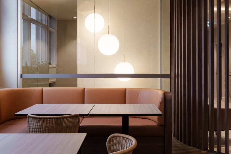 Cognac leather upholstery, timber slat screen, globe pendant lighting, glass partition, woven rattan dining chairs, booth seating layout, acoustic partitioning, hospitality dining, club interior fit-out