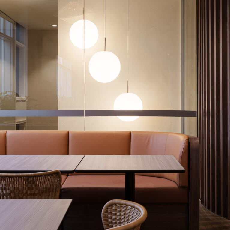 Cognac leather upholstery, timber slat screen, globe pendant lighting, glass partition, woven rattan dining chairs, booth seating layout, acoustic partitioning, hospitality dining, club interior fit-out