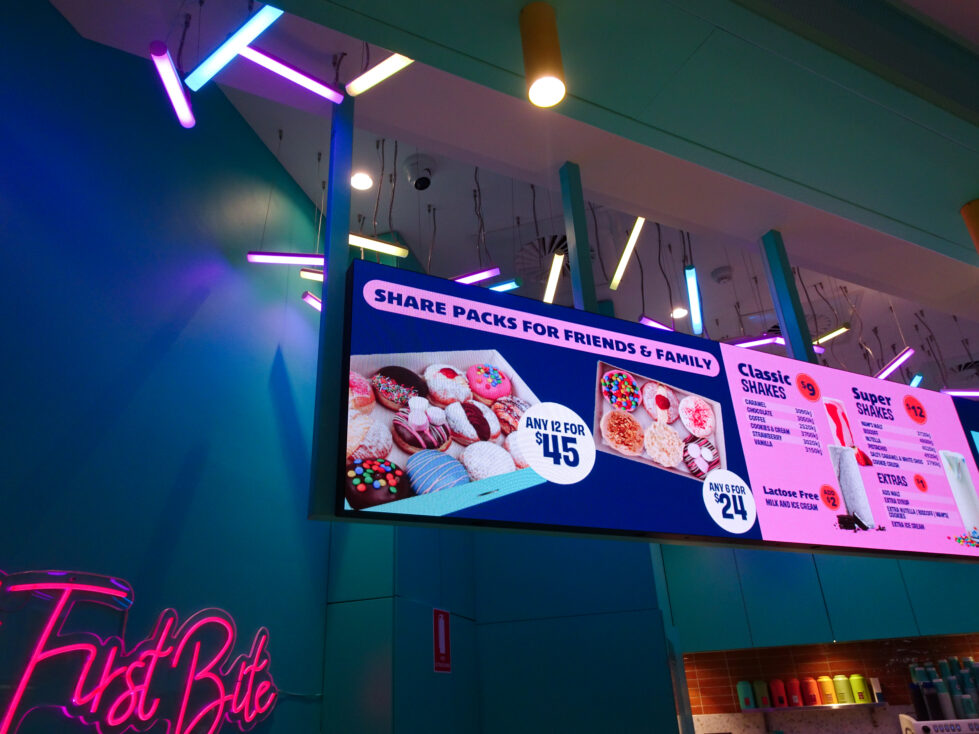 A vibrant ceiling installation energises the space while guiding attention to the illuminated menu.