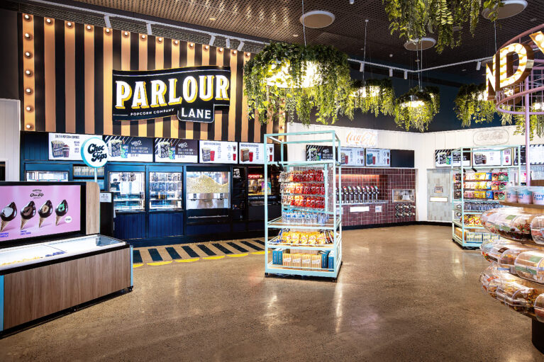 A theatrically lit concessions hub blending playful branding with high-impact merchandising.