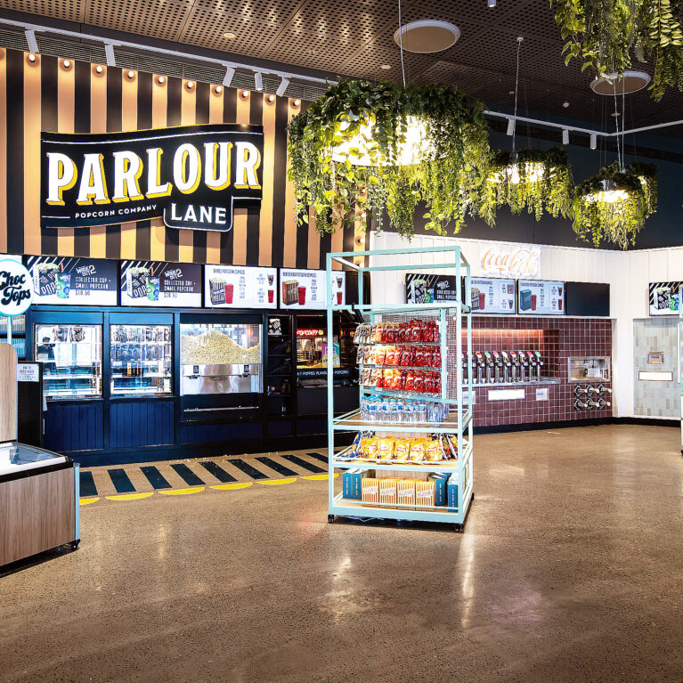 A theatrically lit concessions hub blending playful branding with high-impact merchandising.