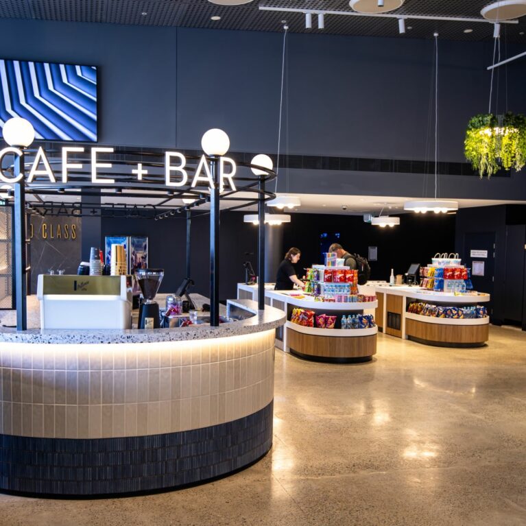 Guests flow seamlessly from ticket to treats, greeted by a contemporary café and bar that encourages a moment of pause. The open island layout and warm finishes invite casual conversation, transforming the typical cinema snack stop into a welcoming experience.