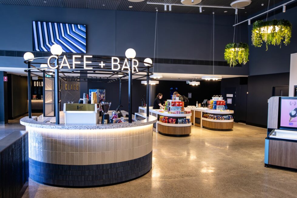 Guests flow seamlessly from ticket to treats, greeted by a contemporary café and bar that encourages a moment of pause. The open island layout and warm finishes invite casual conversation, transforming the typical cinema snack stop into a welcoming experience.