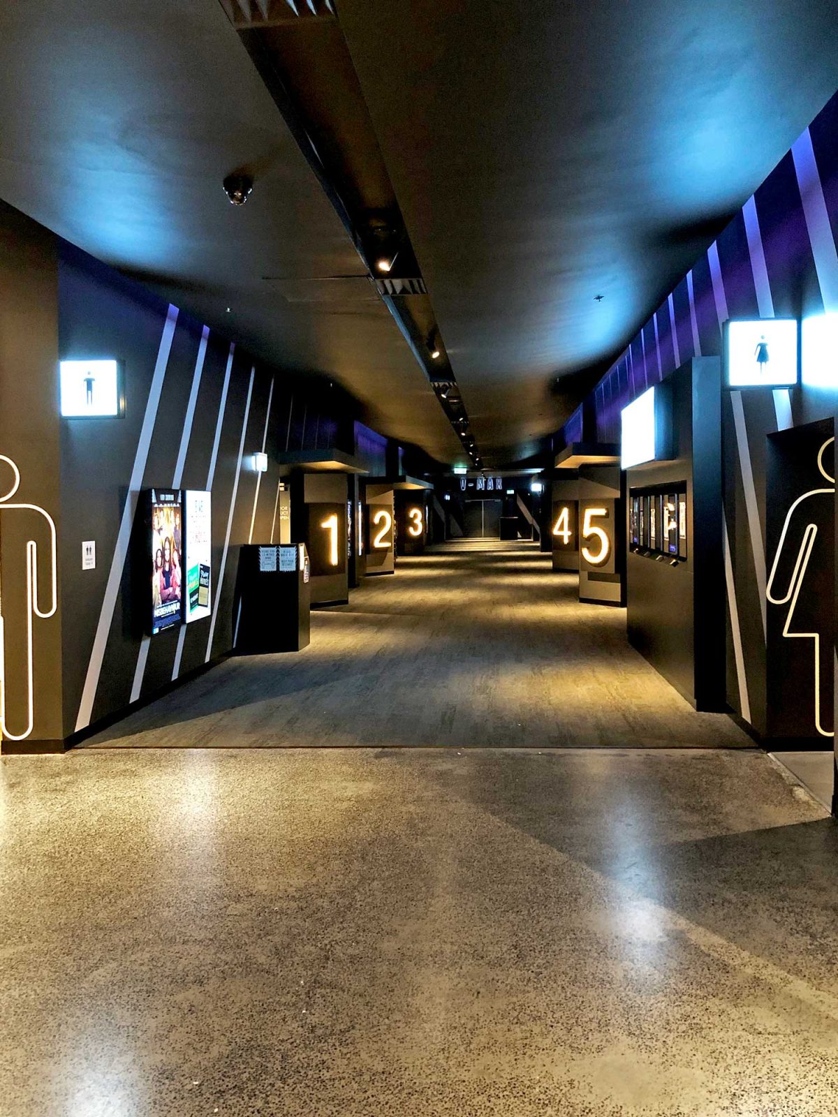 A well-lit cinema concourse with strategic signage and modern lighting for a sleek, functional design.