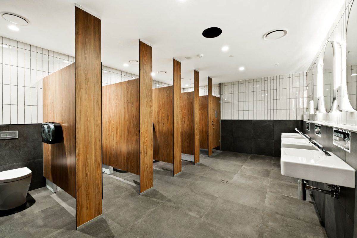 A modern and sleek restroom with warm wood accents, minimalist sinks, and sophisticated tile work.