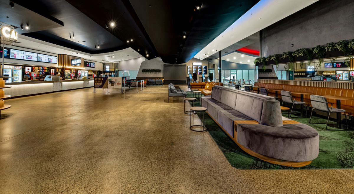 A contemporary cinema lobby with sleek seating, textured walls, and dynamic lighting for an inviting atmosphere.