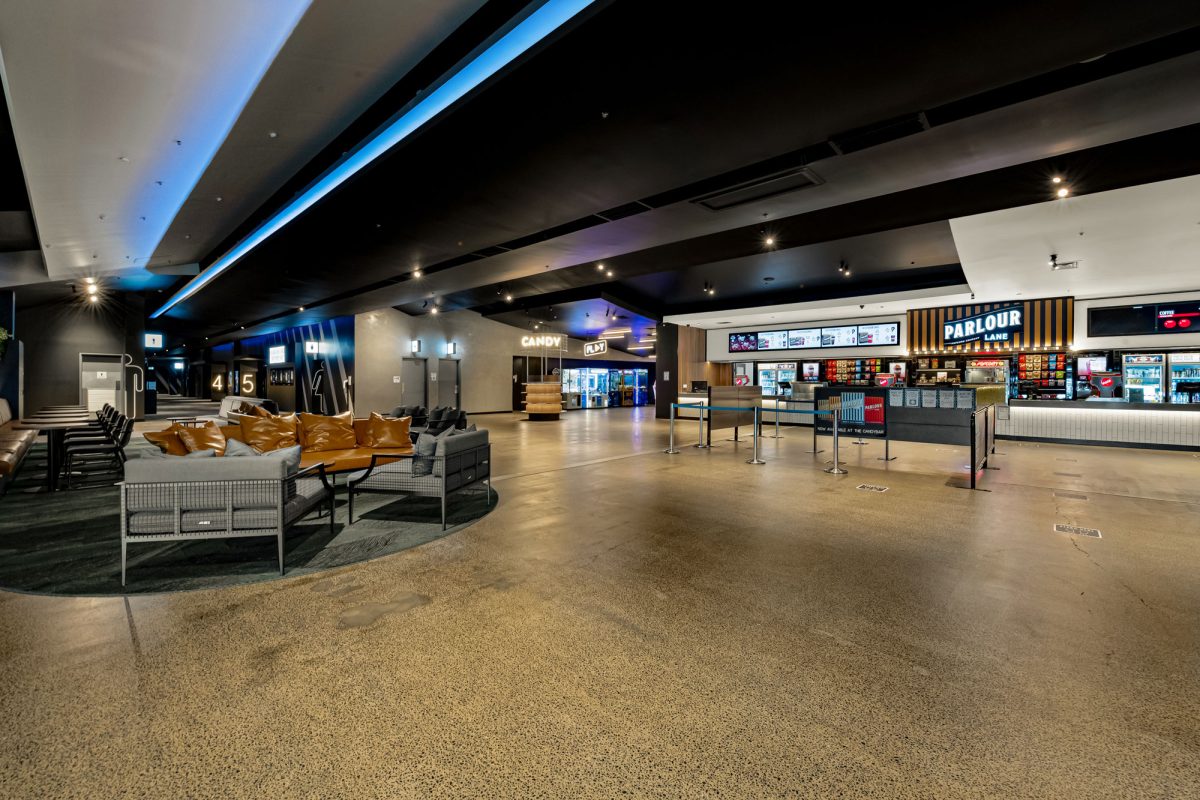 A spacious and modern movie theater lobby featuring the Parlour Lane, comfortable lounges, and sleek lighting.