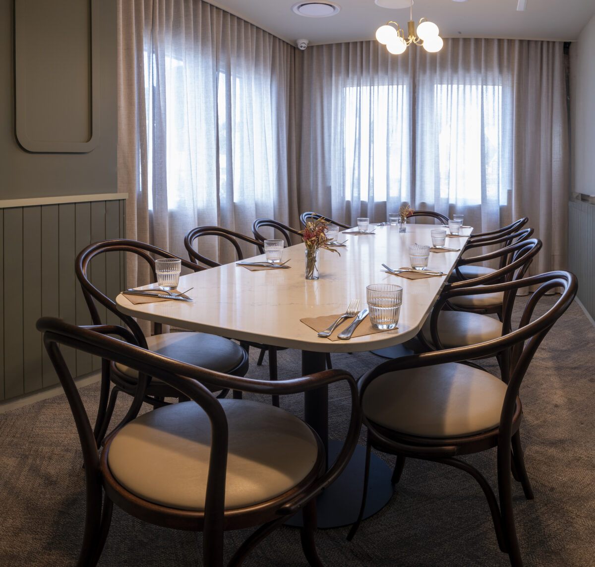 A refined private dining space centred around a sculpted stone-look table and enveloped in soft drapery.