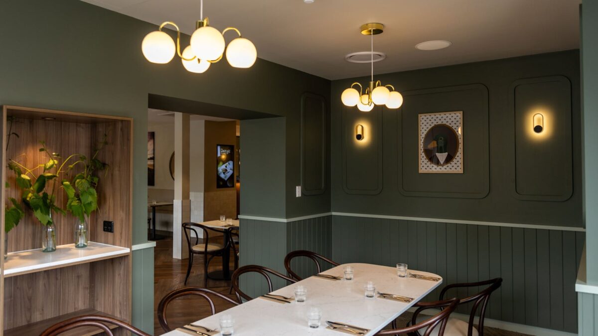 A refined dining nook layered in deep greens, soft curves, and ambient lighting.