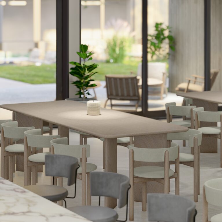 This dining area features timber tables and upholstered chairs in soft neutral tones. The Maximum Viola porcelain kitchen island anchors the space, while large glass doors open to the outdoor lounge, enhancing the connection between interior and exterior settings.