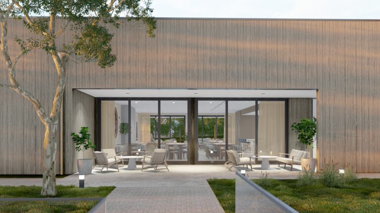 This outdoor lounge features Torino Crazy Paving flooring, sleek timber-framed seating, and a seamless connection to the indoor living room. Large glass doors enhance natural light flow, merging the relaxed exterior with the elegant communal interior.