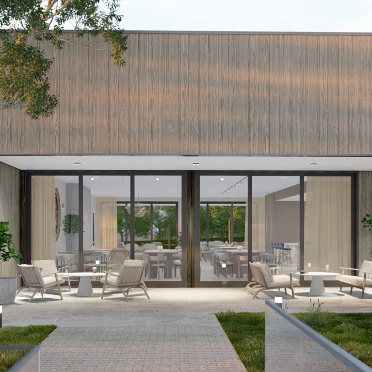 This outdoor lounge features Torino Crazy Paving flooring, sleek timber-framed seating, and a seamless connection to the indoor living room. Large glass doors enhance natural light flow, merging the relaxed exterior with the elegant communal interior.