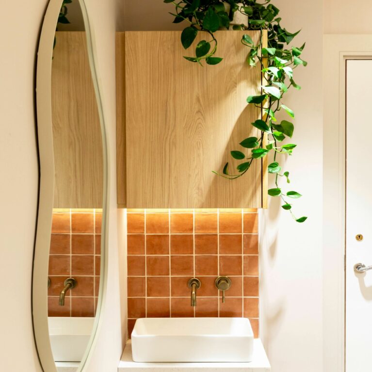 The treatment room’s service station combines practicality and charm. A compact cabinet with warm wood tones pairs with terracotta wall tiles and a streamlined basin, while cascading greenery adds softness, enhancing the cozy and calming atmosphere for clients.