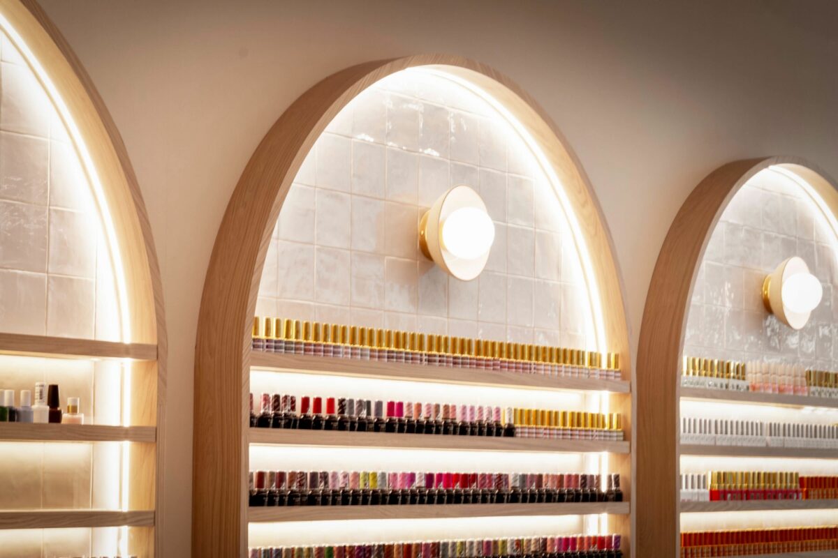 A closer look at the nail polish display reveals arched niches that merge practicality with elegance. Warm backlighting and soft oak framing turn a simple storage solution into a striking visual feature that draws the eye immediately.