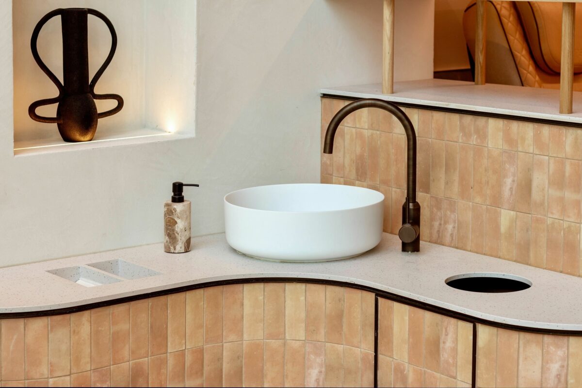 This close-up of the welcome station reveals the meticulous attention to materiality, where warm earthy tiles, a softly textured countertop, and a minimalist basin combine into a functional yet visually striking feature.