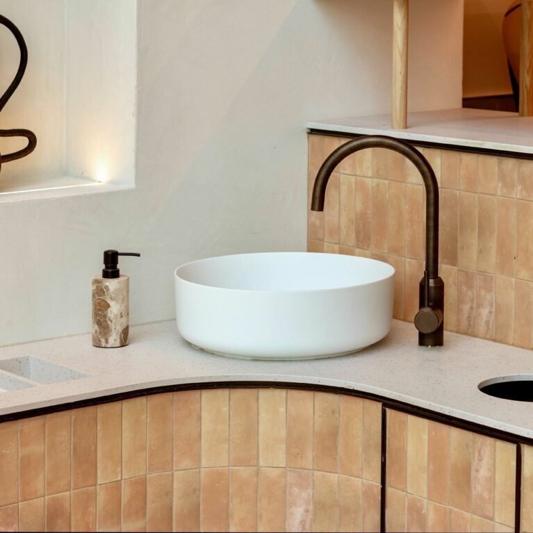 This close-up of the welcome station reveals the meticulous attention to materiality, where warm earthy tiles, a softly textured countertop, and a minimalist basin combine into a functional yet visually striking feature.