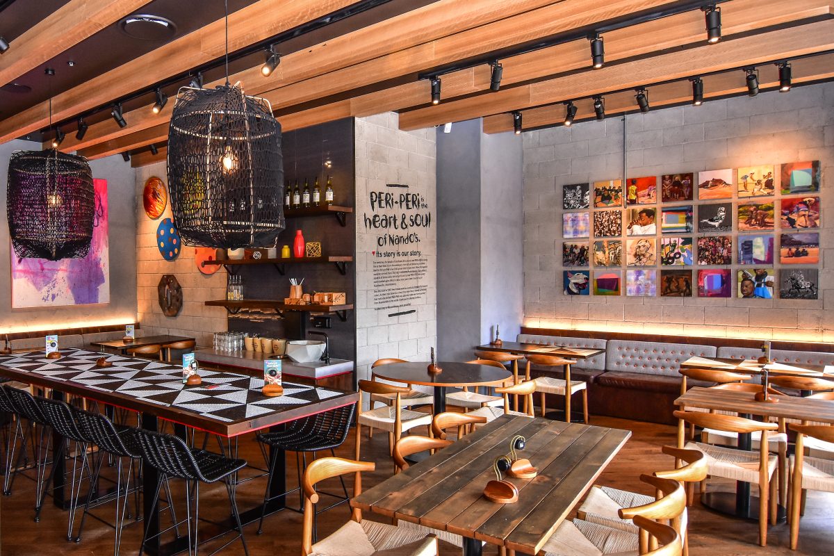 Geometric tiled dining table, basket weave pendant lamps, exposed timber ceiling beams, art gallery wall display, timber restaurant seating, concrete wall finishes.