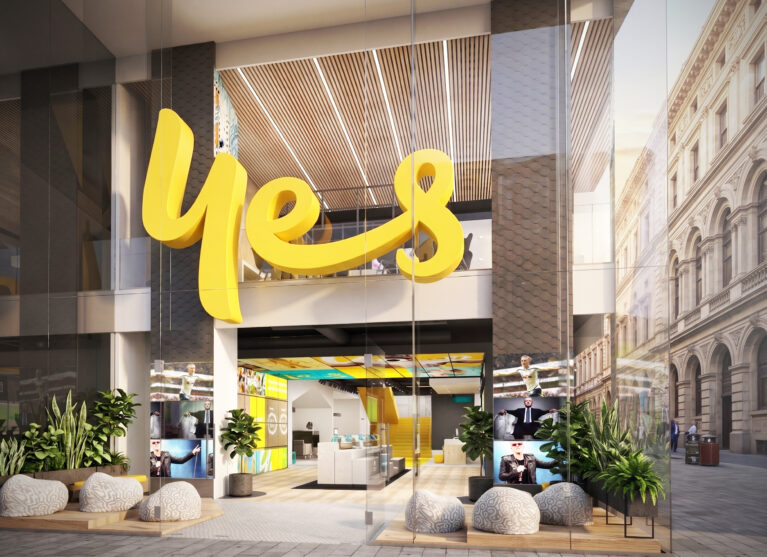 Flagship retail facade, double-height glass storefront, sculptural yellow branding, timber batten ceiling, integrated planter boxes, stone organic seating, digital display entry.