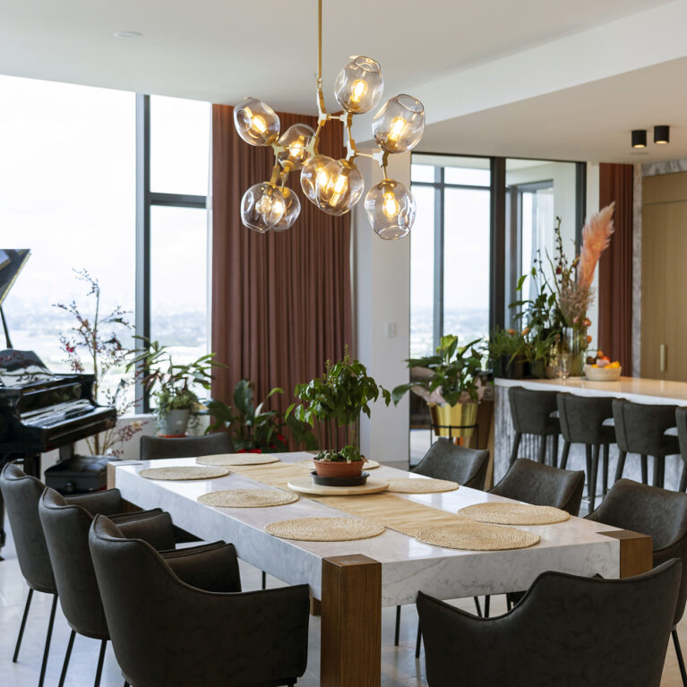 The dining area features a Calacatta marble table with oak legs and a striking modern chandelier, creating a stylish, welcoming space for gatherings. The design seamlessly integrates natural materials with contemporary touches.