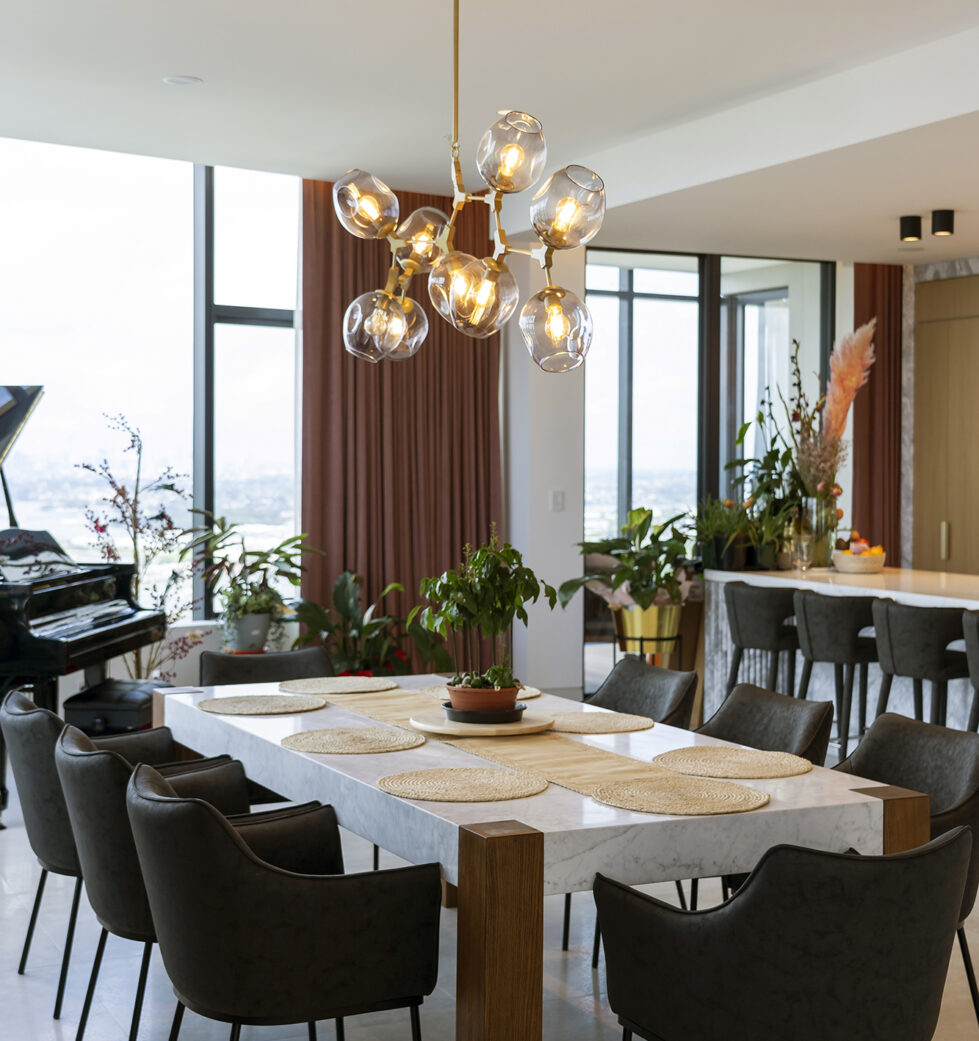 The dining area features a Calacatta marble table with oak legs and a striking modern chandelier, creating a stylish, welcoming space for gatherings. The design seamlessly integrates natural materials with contemporary touches.