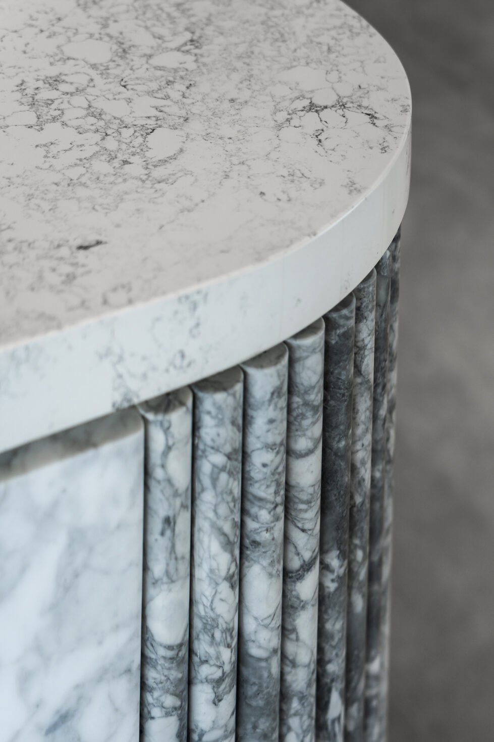 A close-up of the island reveals the exquisite veining of Calacatta marble, accentuated by vertical fluted detailing along the base. This refined texture adds a dynamic, tactile quality to the kitchen’s luxurious design.