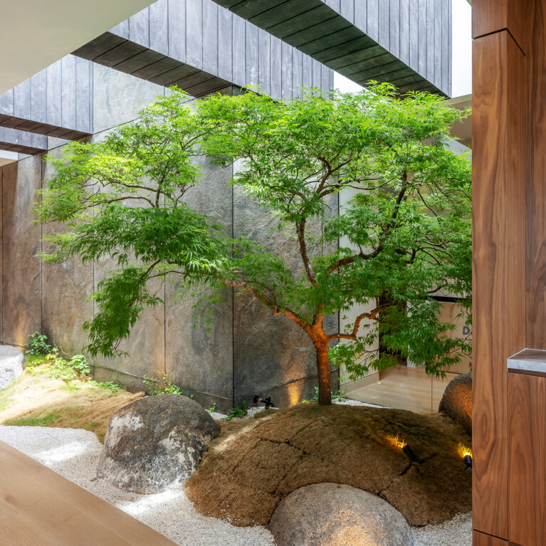 A serene Japanese-inspired courtyard with natural stone, greenery, and textured walls, creating a tranquil escape within the penthouse.