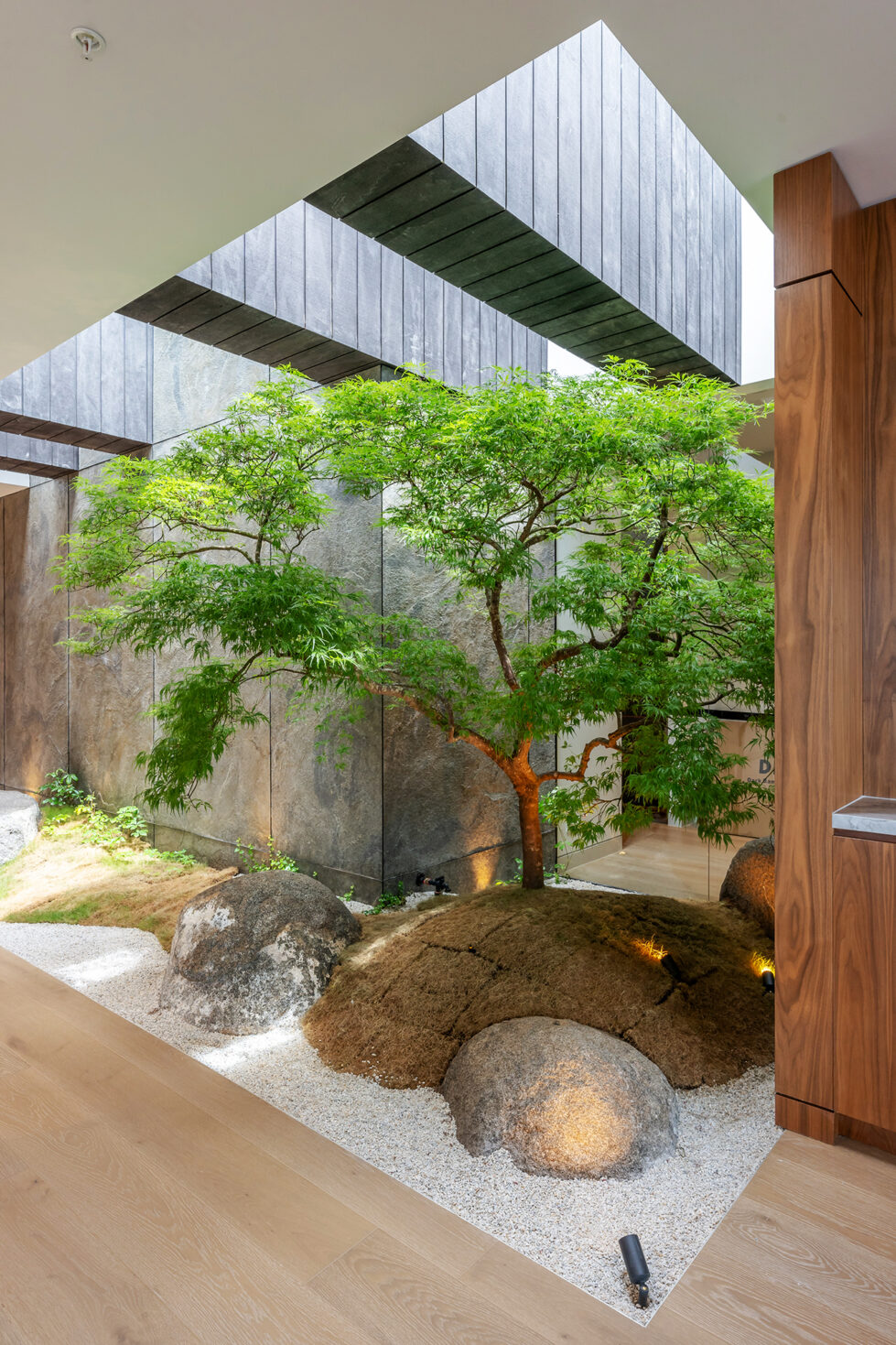 A serene Japanese-inspired courtyard with natural stone, greenery, and textured walls, creating a tranquil escape within the penthouse.