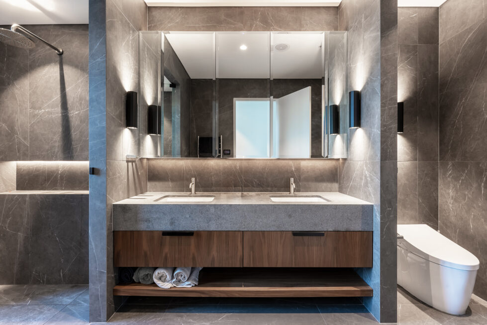 A luxurious master ensuite bathroom with Pietra Grey tiles, American Walnut cabinetry, and soft integrated lighting.