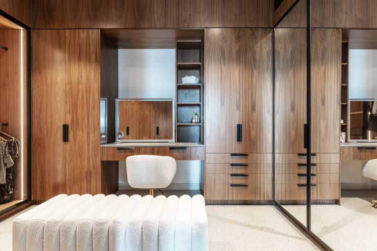 A luxurious master robe featuring walnut cabinetry, integrated lighting, and a sleek makeup station, blending functionality with sophisticated design.