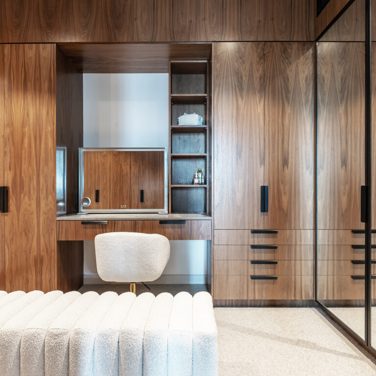 A luxurious master robe featuring walnut cabinetry, integrated lighting, and a sleek makeup station, blending functionality with sophisticated design.