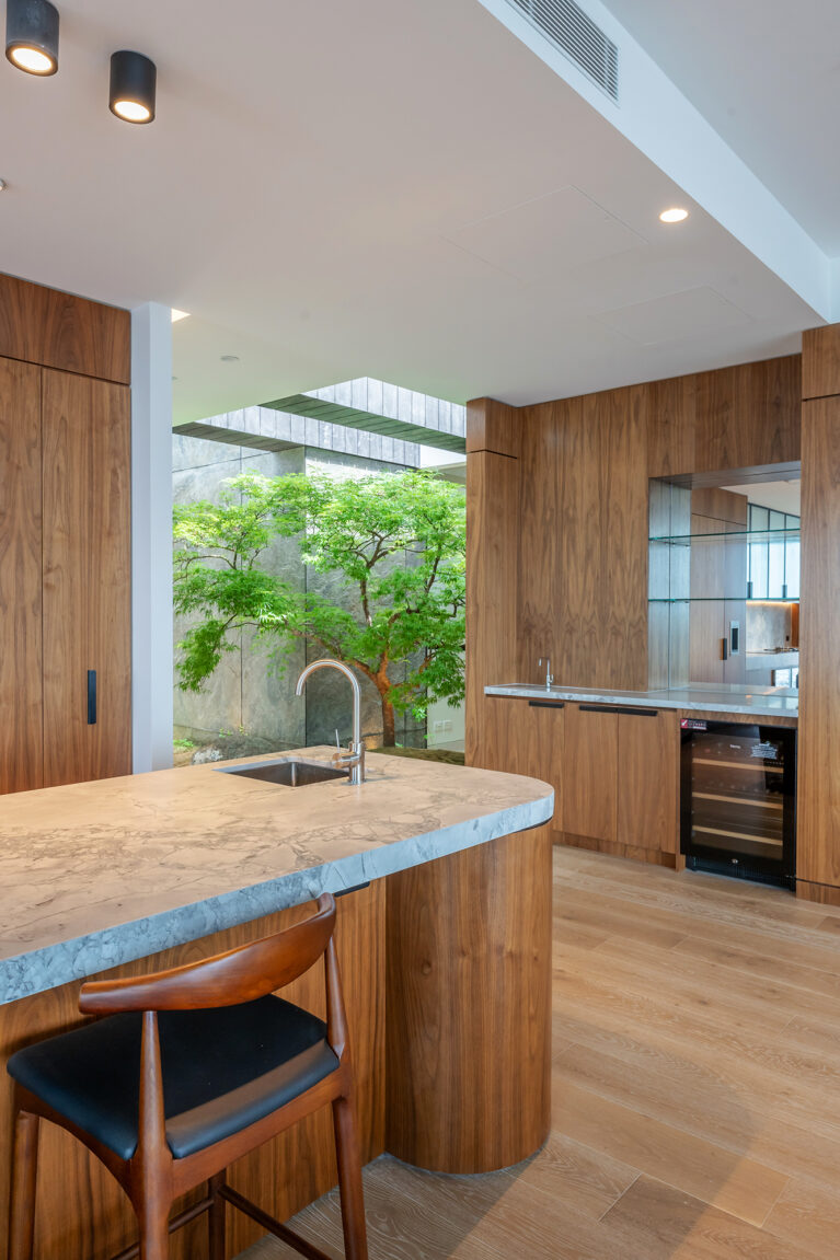 An elegant kitchen and bar area that flows seamlessly into a serene Japanese-inspired courtyard, blending luxury and nature.