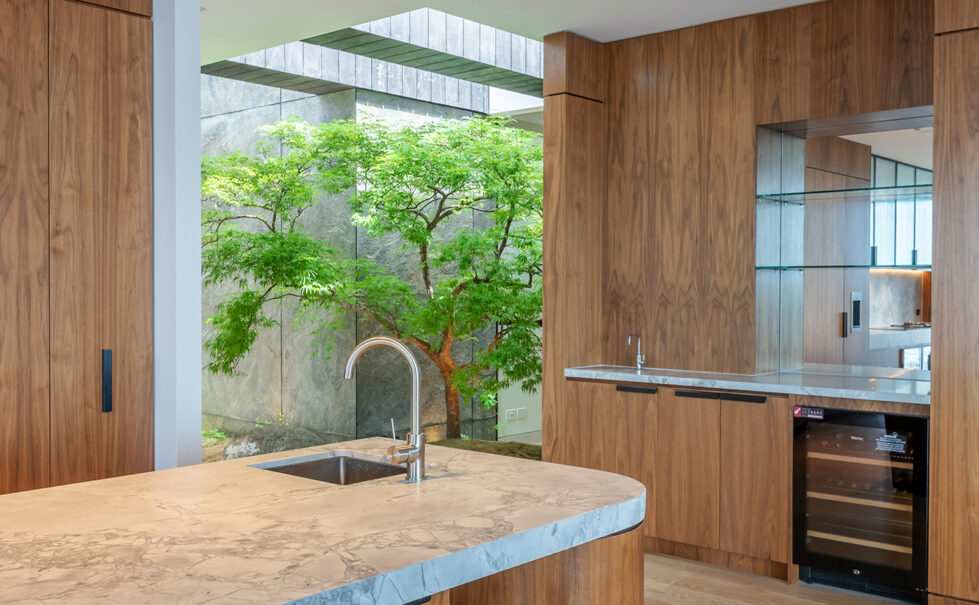 An elegant kitchen and bar area that flows seamlessly into a serene Japanese-inspired courtyard, blending luxury and nature.