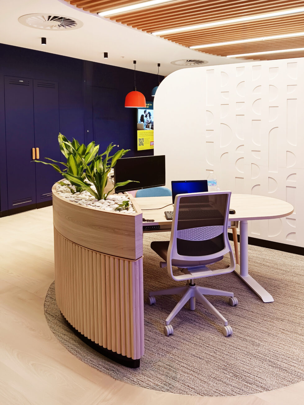 Inviting client advisory desks with a modern curved design, soft textures, and a featured leafy planter for a fresh touch.